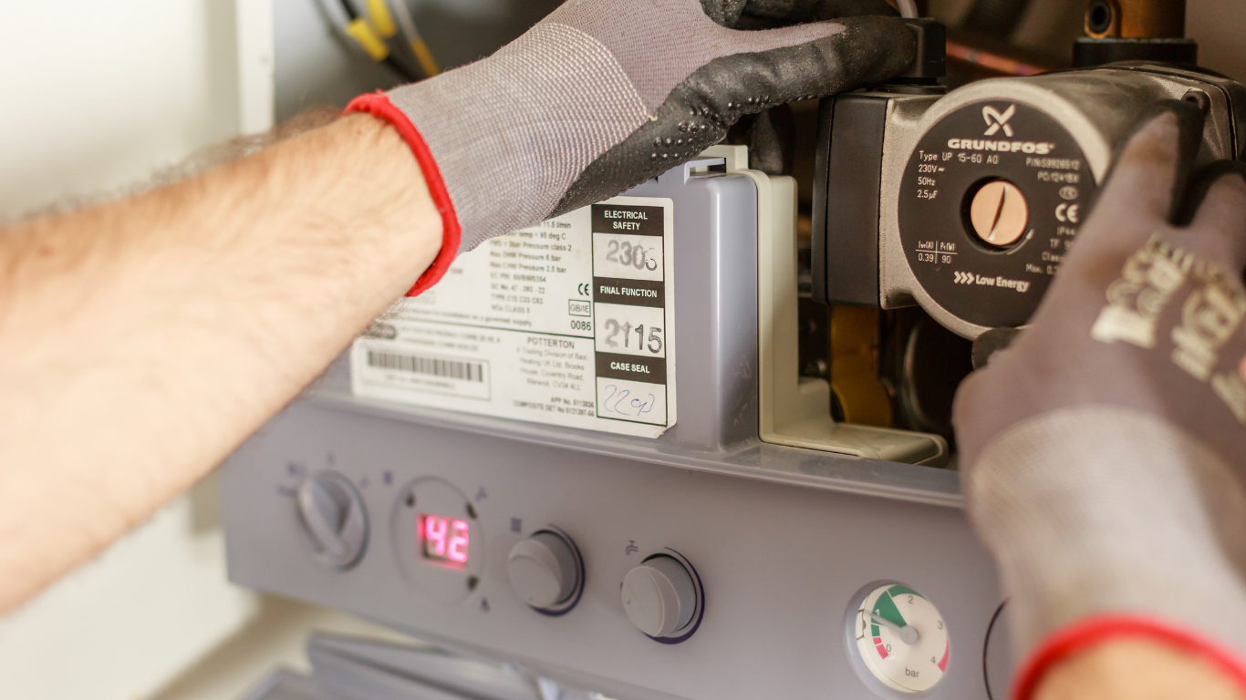 Heating engineer working on a circulation pump inside a boiler. Underfloor heating manifold with circulation pump, control valves and connected pipework.