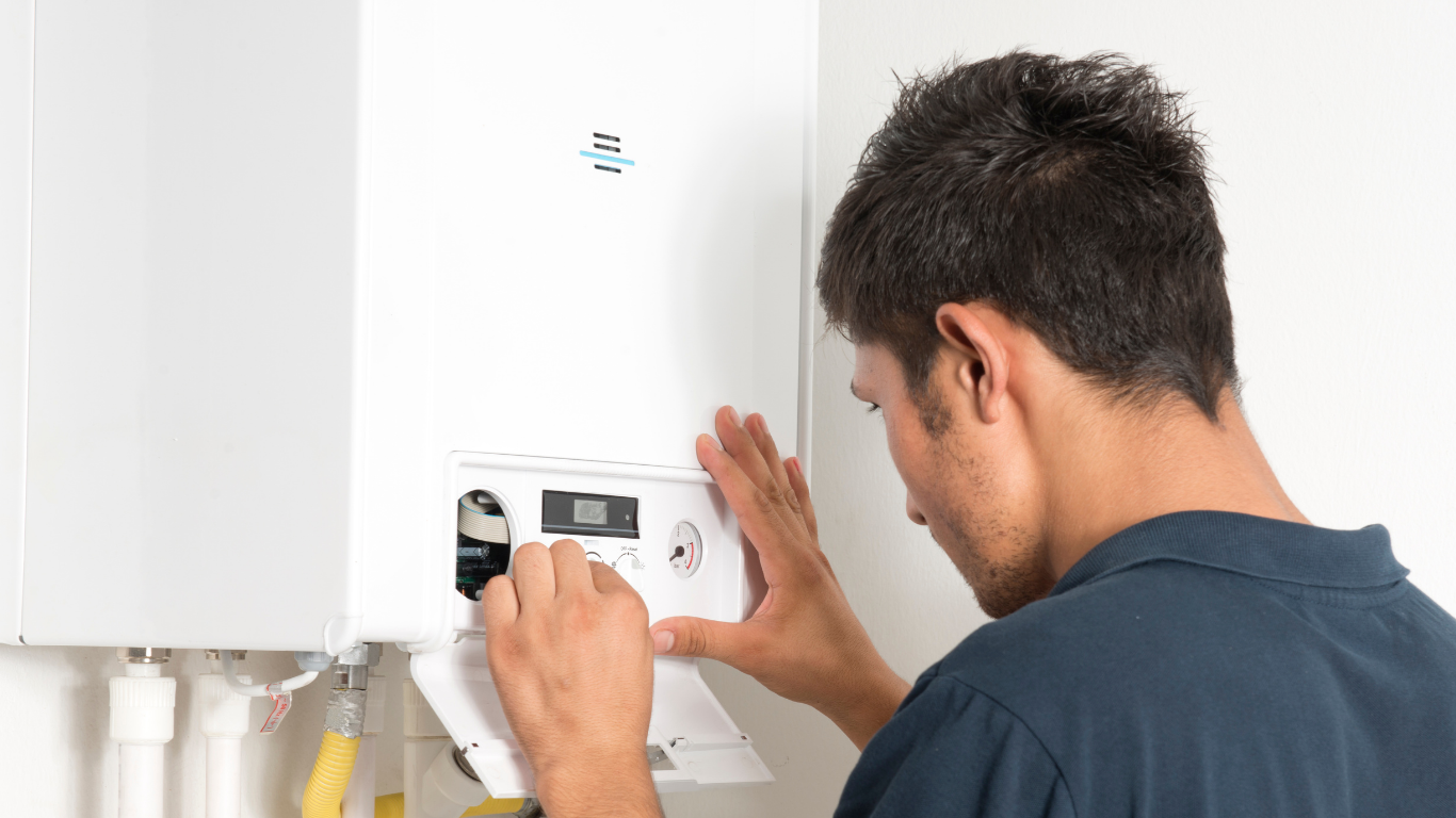 Plumber adjusting waste pipework beneath a double kitchen sink.