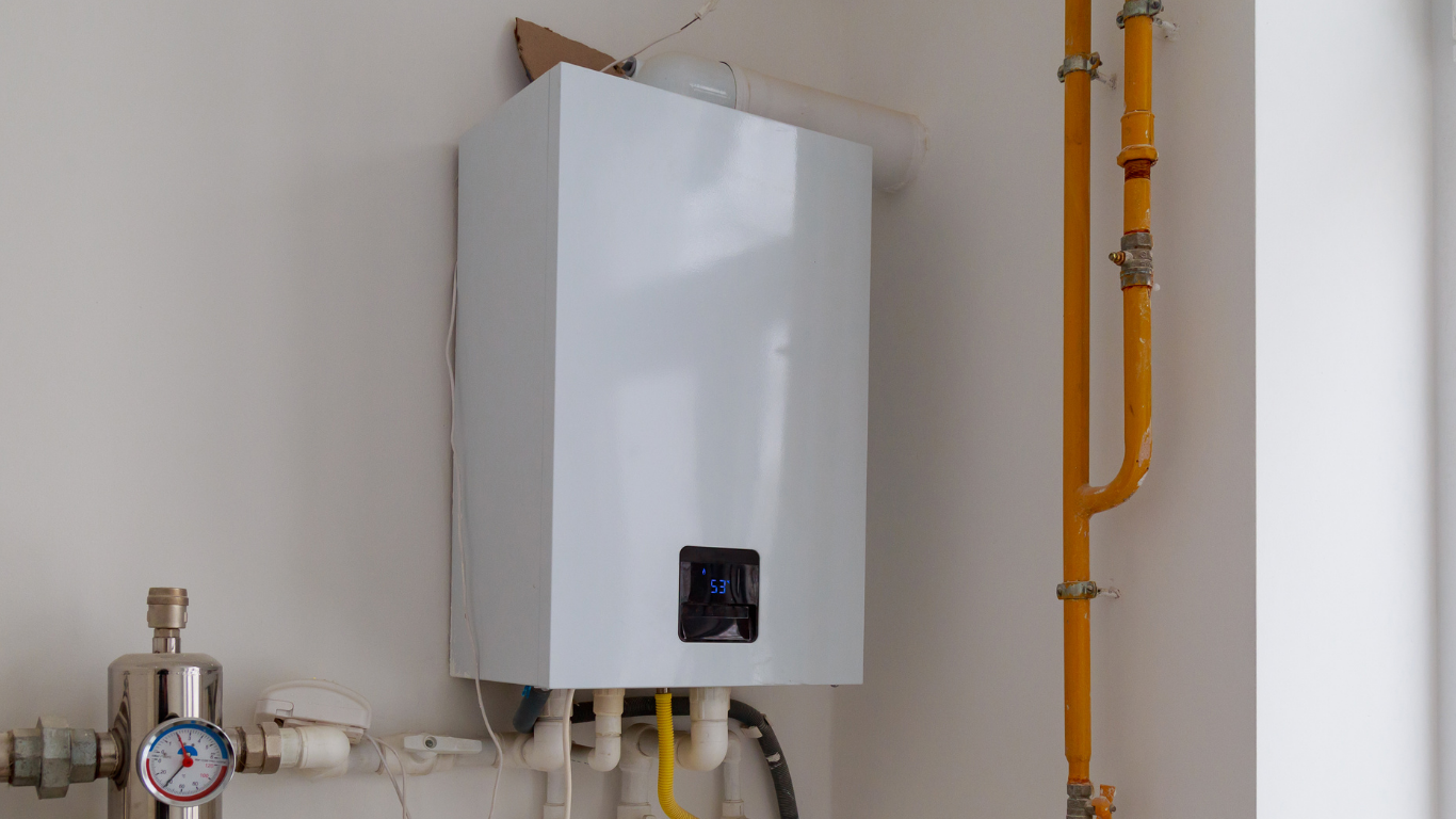 Wall mounted boiler with exposed copper pipework. Plumber adjusting waste pipework beneath a double kitchen sink.